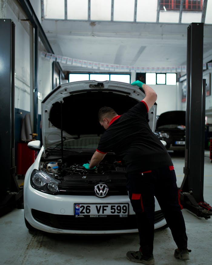 A mechanic works on a Volkswagen engine in an indoor garage setting, showcasing automotive repair skills.
